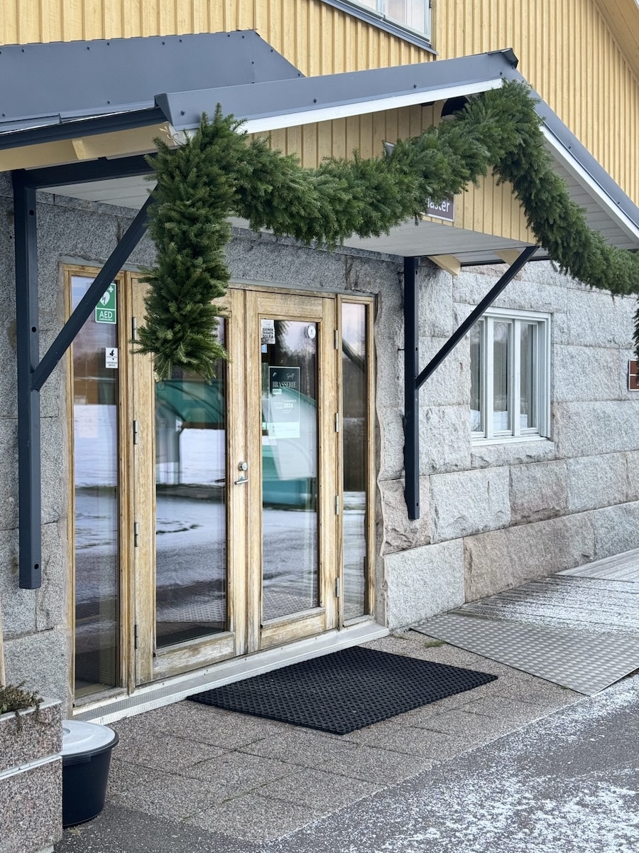 Brasserie Golfin sisäänkäynti: lasiovet, havuköynnös ja klubirakennuksen kivijalka